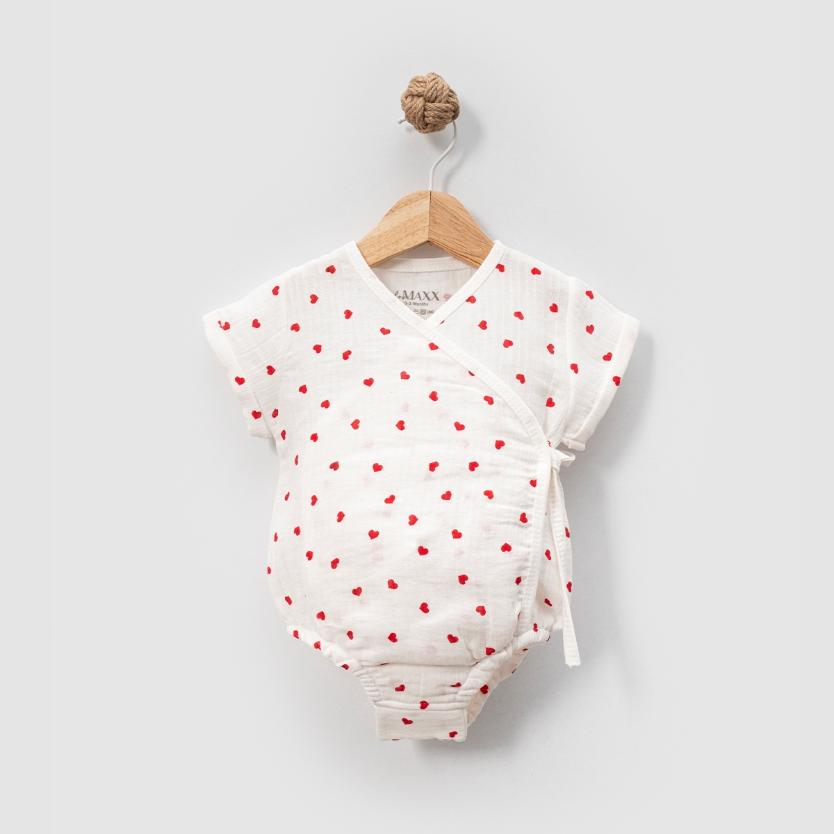 romper-muselina-fetite-inimioare Romper pentru fetițe din muselină albă cu imprimeu de inimioare roșii și închidere laterală.