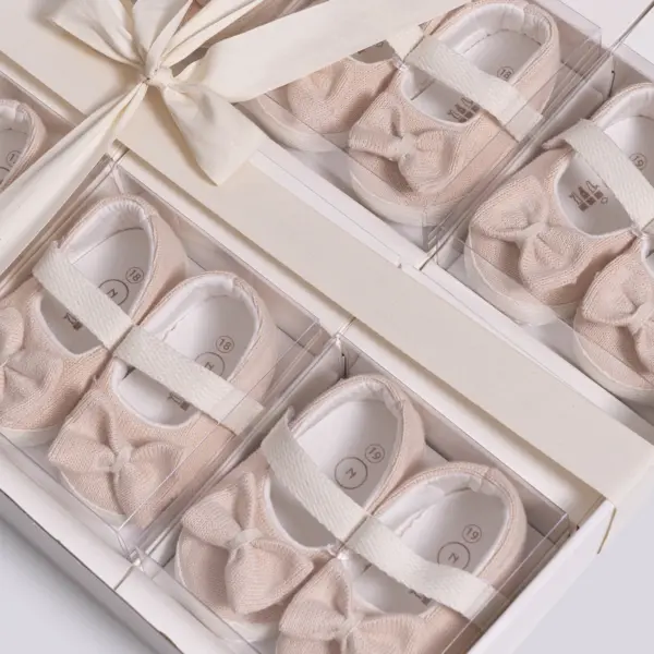 Pereche de pantofiori eleganți pentru bebeluși tip balerini cu fundiță bej și bareta elastică în cutie cadou premium.