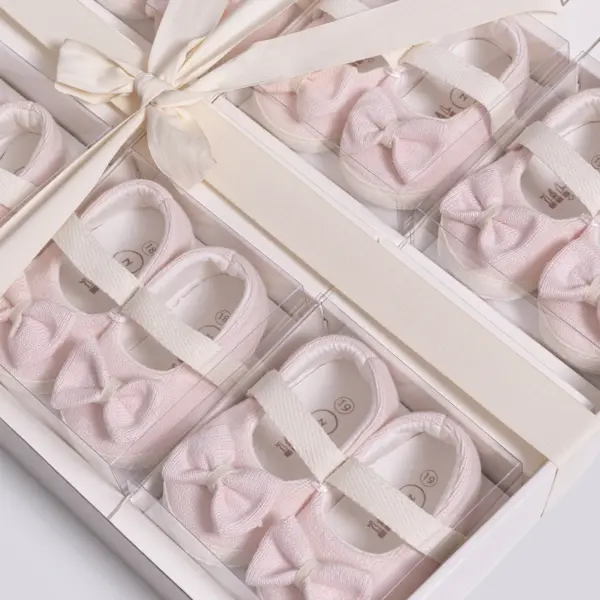 Pereche de pantofiori eleganți pentru bebeluși tip balerini cu fundiță roz și bareta elastică în cutie cadou premium.