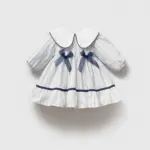 Rochiță albă cu dungi albastre și imprimeu floral pentru fetițe, stil Marine Chic cu guler rotund și două fundițe.