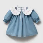 Rochiță din denim albastru moale pentru fetițe cu guler alb mare brodat cu fluturi, flori și fundiță din satin.